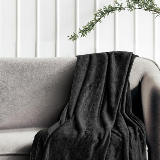 Black faux fur throw blanket draped over a gray couch with a plant in the background.