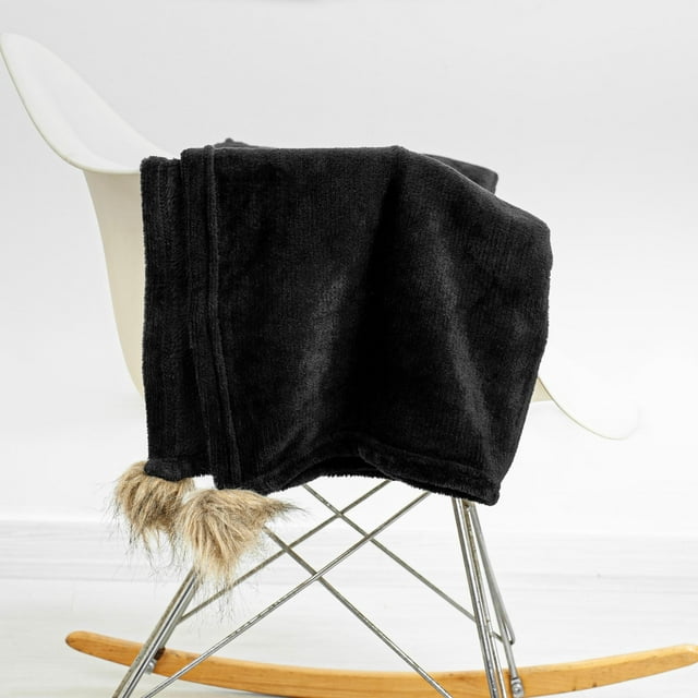 A black rocking chair blanket sitting on a rocking chair.