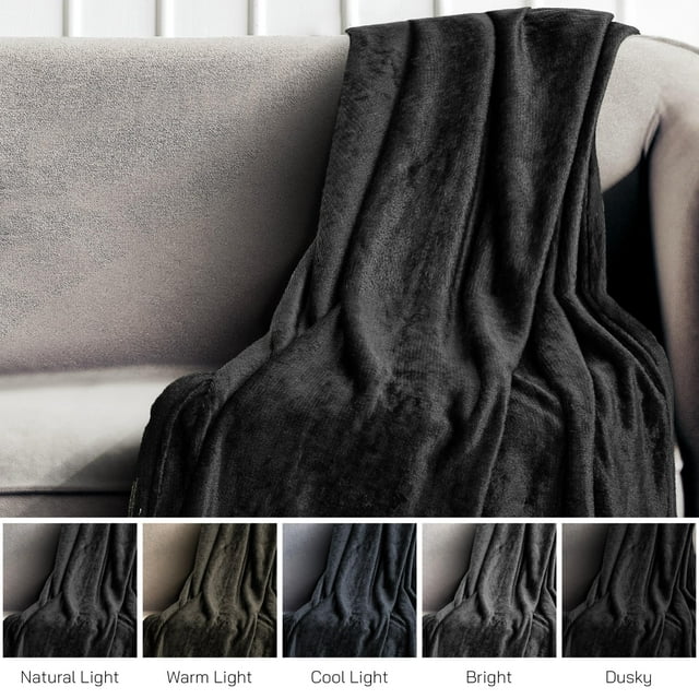 A soft, black blanket sitting on top of a couch.